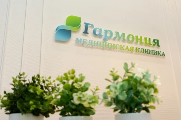 Растения в горшках на фоне стены с логотипом клиники